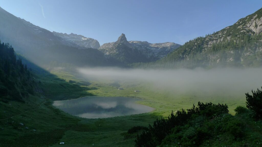 Frühmorgendlicher Blick über den Funtensee im Nationalpark Berchtesgaden mit Nebelbank und umliegenden Alpen