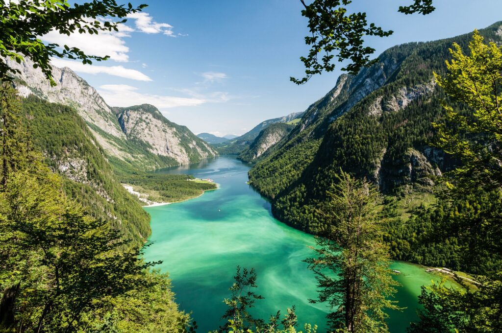 Panoramablick auf den smaragdgrünen Königssee im Nationalpark Berchtesgaden, eingerahmt von steilen Berghängen und dichtem Wald
